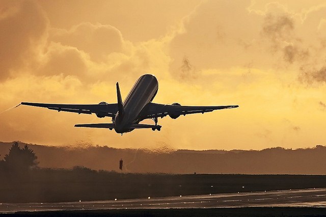 A Boeing 767 plane taking off at sunset.