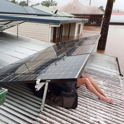 People sheltering from rain and floods under roof-top solar panels.