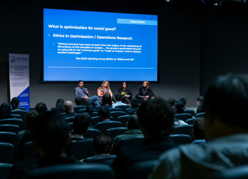 Panel members in front of a crowd of people