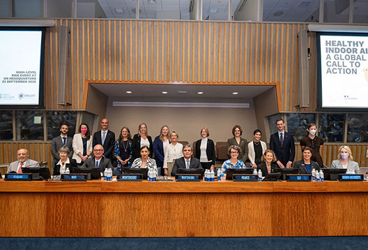 Delegates – including Anna-Maria Arabia and Professor Lidia Morawska – seated and standing in a formal conference room at the United Nations headquarters during the 'Healthy Indoor Air: A Global Call to Action' event on 24 September 2025. Nameplates for  Montenegro and France are visible. Two large screens display the event title and date.