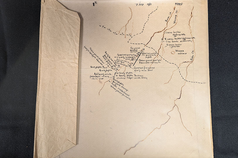 A transparency sheet with a hand-drawn geological map on it, overlaid on a yellowed piece of paper.