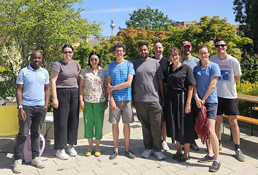The Australian Lindau delegation of young scientists take a group photo in a park with a tower visible on the skyline in the background