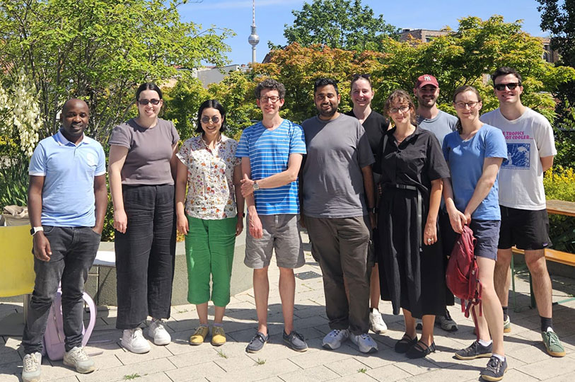 The Australian Lindau delegation of young scientists takes a group photo in a park with a tower visible on the skyline