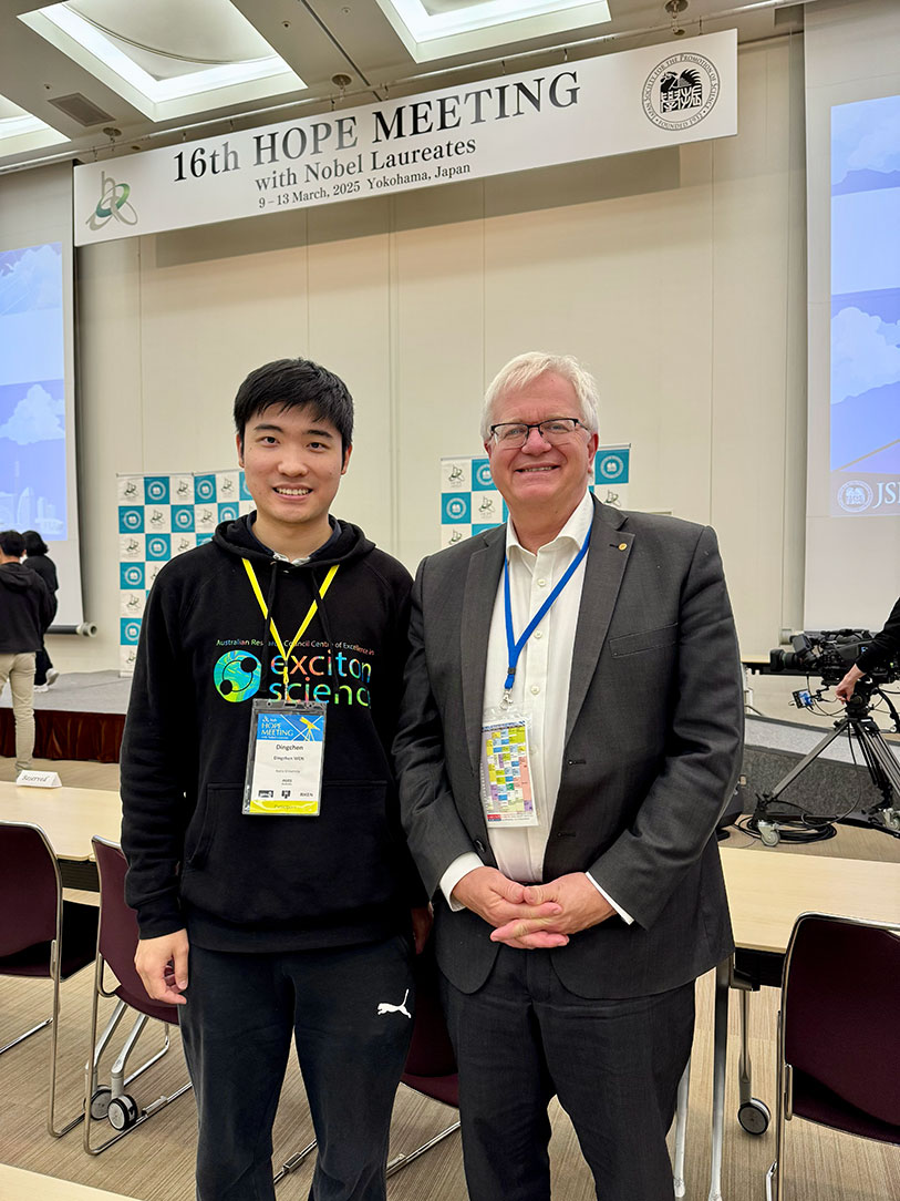 Dr Dingchen Wen and Professor Brian Schmidt pose for a photo beneath a sign that reads '16th HOPE meeting with Nobel Laureates 9–13 March 2025 Yokohama Japan'. Both are smiling and wearing conference lanyards.