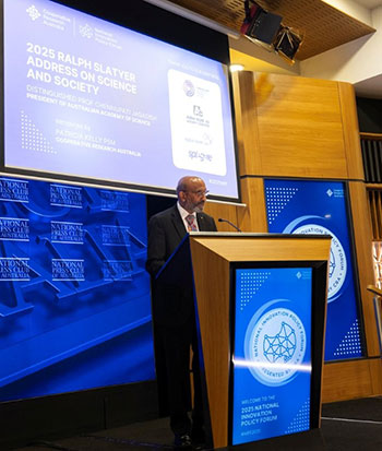 Professor Jagadish behind a lectern in front of a screen that reads '2025 Ralph Slatyer Address on Science and Society'.