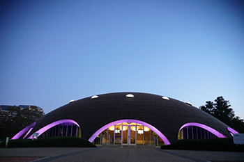 Shine Dome underneath a dark blue sky at dusk with purple lights illuminating the arches